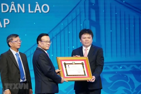 Phó Thủ tướng chính phủ Lào Somdee Duangdee (giữa) trao tặng Huân chương Lao động hạng Nhất cho LaoVietBank. (Ảnh: Xuân Tú/TTXVN)