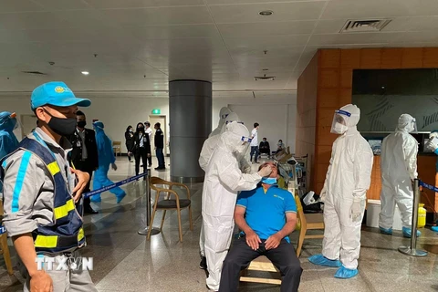 Nhân viên y tế lấy mẫu xét nghiệm cho người làm việc tại sân bay Tân Sơn Nhất ngày 6/2. (Ảnh: TTXVN phát)