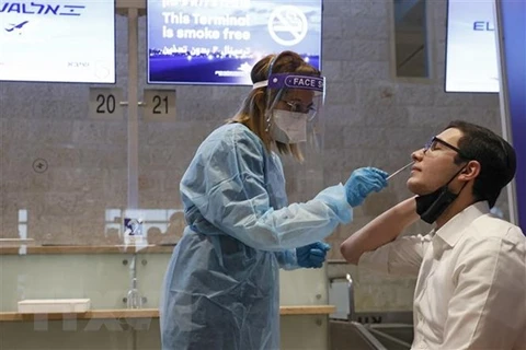 Nhân viên y tế lấy mẫu xét nghiệm COVID-19 cho người dân tại Tel Aviv, Israel. (Ảnh: AFP/TTXVN) 