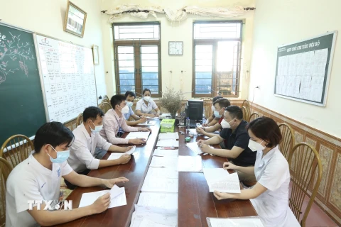 Thành viên trạm y tế lưu động họp, triển khai kế hoạch tại điểm phong toả Thị trấn Quốc Oai. (Ảnh: Minh Quyết/TTXVN)