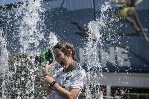 Người dân tránh nóng tại vòi phun nước ở Melbourne, Australia. (Ảnh: THX/TTXVN)
