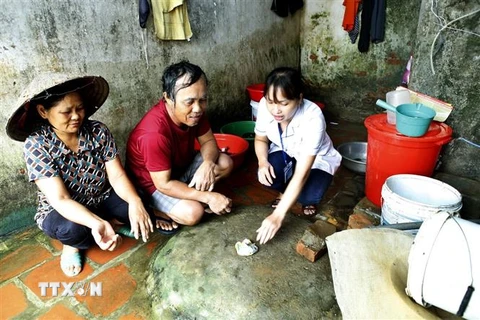 Hướng dẫn người dân vệ sinh nguồn nước phòng chống dịch bệnh. (Ảnh: TTXVN/Vietnam+)