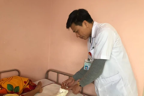 Bác sỹ Hoàng thăm khám chân cho cháu bé. (Ảnh: PV/Vietnam+)