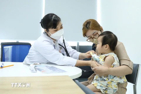 Nhân viên y tế khám cho trẻ trước khi tiêm chủng. (Ảnh: Minh Quyết/TTXVN)