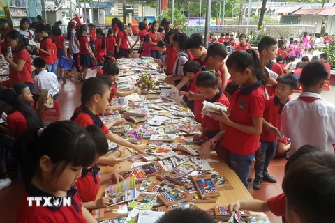 Các em học sinh đọc sách tại Ngày hội. (Ảnh: Hương Thu/TTXVN)