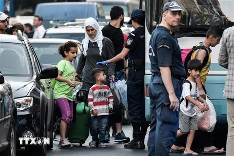 Cảnh sát Hy Lạp áp giải người di cư rời khỏi các khu nhà chiếm dụng bất hợp pháp ở trung tâm thủ đô Athens. (Ảnh: AFP/TTXVN)