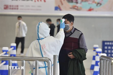 Nhân viên kiểm tra thân nhiệt của hành khách tại nhà ga tàu hỏa ở Vũ Hán, tỉnh Hồ Bắc, Trung Quốc. (Ảnh: THX/TTXVN)