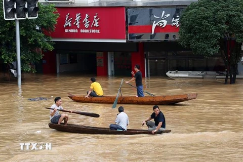 Người dân đi thuyền qua khu vực ngập lụt do mưa lớn tại Khu tự trị dân tộc Choang Quảng Tây, Trung Quốc. (Ảnh: THX/TTXVN)