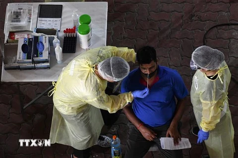 Nhân viên y tế lấy mẫu dịch xét nghiệm COVID-19 cho người dân tại Singapore. (Ảnh: AFP/TTXVN)