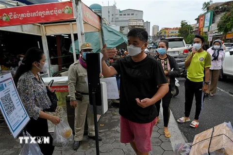 Kiểm tra thân nhiệt phòng lây nhiễm COVID-19 trước khi vào chợ tại Phnom Penh, Campuchia. (Ảnh: AFP/TTXVN)