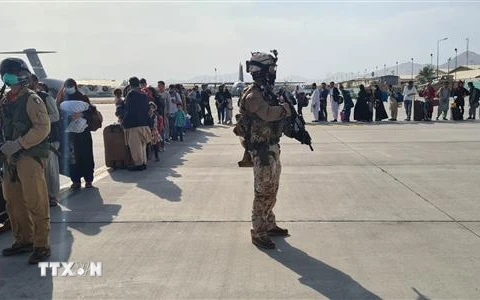 Binh sỹ đảm bảo an ninh khi người dân lên máy bay quân sự của Italy tại sân bay Kabul để sơ tán khỏi Afghanistan. (Ảnh: AFP/TTXVN)