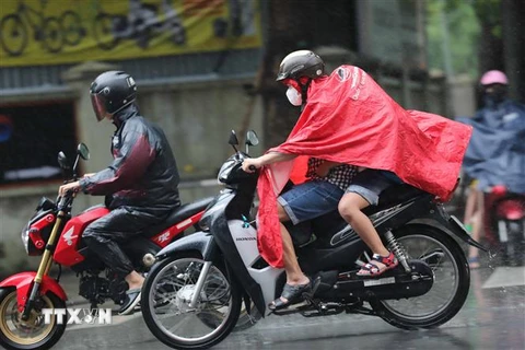 Người dân Hà Nội mặc áo mưa di chuyển trong cơn mưa sáng 11/8. (Ảnh: Thanh Tùng/TTXVN)