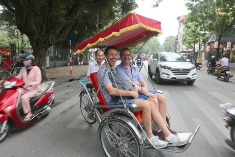 Khách du lịch thích thú khi trải nghiệm phương tiện xích lô trên đường phố Hà Nội. (Ảnh: Thành Đạt/TTTXVN) 