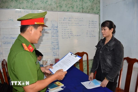 Cơ quan Cảnh sát điều tra Công an tỉnh tống đạt quyết định khởi tố bị can Nguyễn Thị Thanh Thúy. (Ảnh Công Trí/TTXVN)