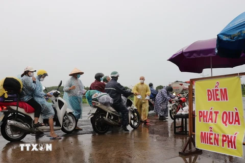 Người dân đội mưa hỗ trợ phần cơm miễn phí tiếp sức cho người dân các tỉnh phía Nam về quê. (Ảnh: Phạm Cường/TTXVN)