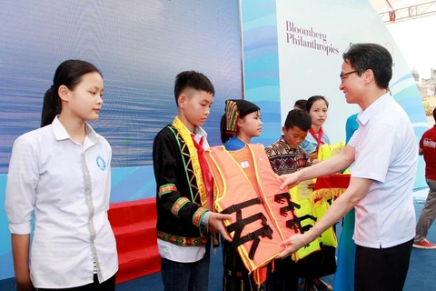 Phó Thủ tướng Vũ Đức Đam tặng áo phao cho đại diện các em học sinh các trường phải đi học qua sông. (Ảnh: PV/Vietnam+)