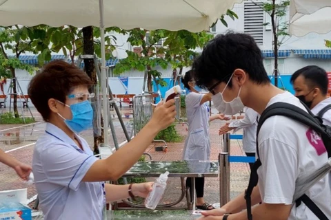 Thí sinh thực hiện sát khuẩn, đo thân nhiệt phòng dịch COVID-19 trước khi vào phòng thi tốt nghiệp trung học phổ thông đợt 1.(Ảnh: CTV/Vietnam+)