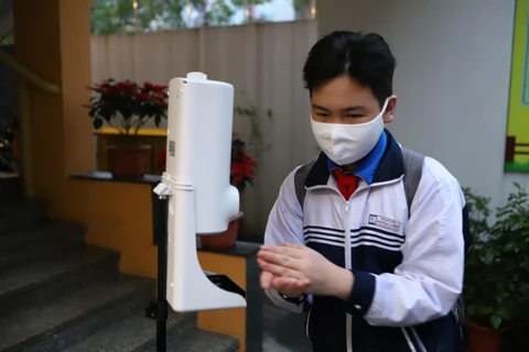 Học sinh thực hiện khử khuẩn trước khi vào lớp khi đi học trực tiếp trở lại. (Ảnh: Nguyễn Nam/Vietnam+)