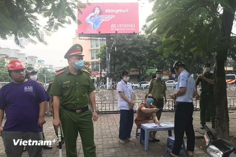 Lực lượng chức năng của Hà Nội xử phạt người không đeo khẩu trang tại nơi công cộng. (Ảnh: Đức Duy/Vietnam+)