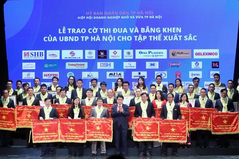 Chủ tịch Ủy ban Nhân dân thành phố Hà Nội Nguyễn Đức Chung trao bằng khen của thành phố cho các doanh nghiệp đạt thành tích xuất sắc. (Ảnh: Danh Lam/TTXVN) 