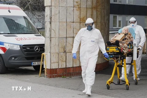 Nhân viên y tế chuyển bệnh nhân COVID-19 vào bệnh viện ở Warsaw, Ba Lan. (Ảnh: AFP/TTXVN) 