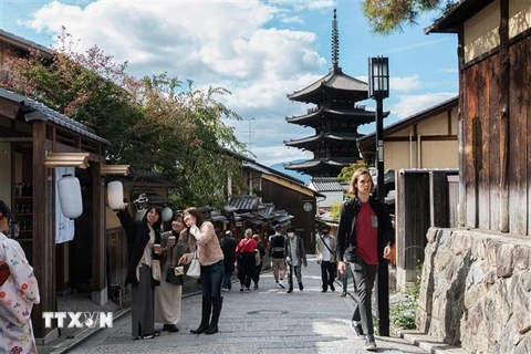 Du khách chụp ảnh trên con đường lát đá dành cho người đi bộ ở Kyoto, Nhật Bản. (Ảnh: AFP/TTXVN)