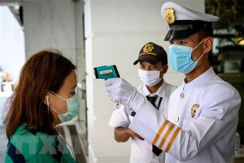 Nhân viên an ninh kiểm tra thân nhiệt người dân trước cửa một tòa nhà nhằm ngăn chặn sự lây lan của dịch COVID-19 tại Bangkok, Thái Lan. (Nguồn: AFP/TTXVN)
