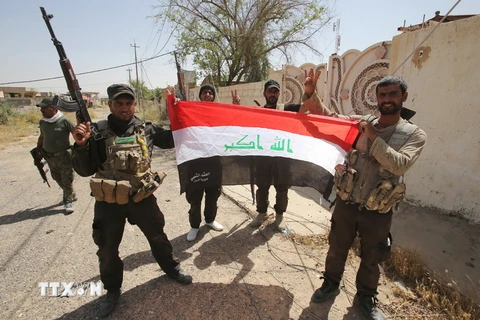 Lực lượng dân quân dòng Shiite giơ cao quốc kỳ Iraq sau khi giành lại quyền kiểm soát thành phố Baiji từ IS ngày 7/6. (Ảnh: AFP/TTXVN)