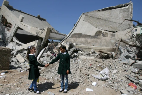 Hai bé gái đứng trước ngôi trường bị phá hủy hoàn toàn do chiến tranh ở dải Gaza. (Ảnh: UNICEF)
