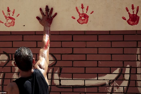 Một người đàn ông đánh dấu lên tường để ghi nhớ ngày hiến sinh. (Ảnh: Reuters)