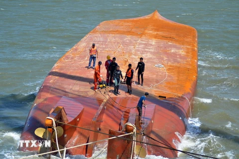 Lực lượng cứu hộ tiến hành móc cáp vào thân tàu Hoàng Phúc 18 để triển khai công tác trục vớt. (Ảnh: TTXVN)
