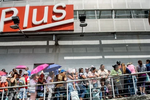 Người dân Venezuela xếp hàng chờ mua đồ bên ngoài một siêu thị ở Caracas. (Nguồn: AFP/TTXVN)