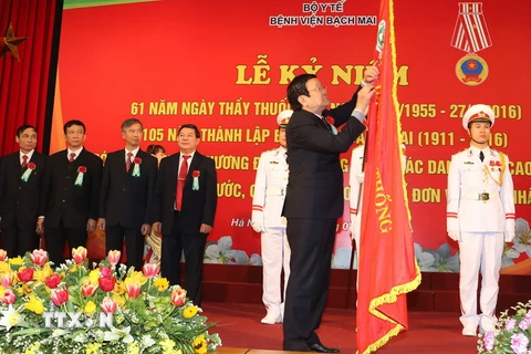  Chủ tịch nước Trương Tấn Sang gắn Huân chương Độc Lập hạng Ba lên lá cờ truyền thống của Bệnh viện Bạch Mai. (Ảnh: Nguyễn Khang/TTXVN)