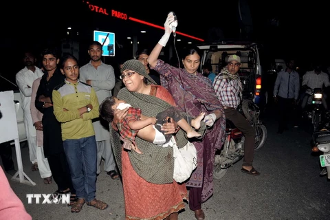 Chuyển một em nhỏ bị thương khỏi hiện trường vụ nổ bom. (Ảnh: AFP/ TTXVN) 