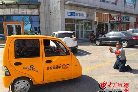 Nhân viên bảo vệ quỳ gối ngăn nữ tài xế đỗ sai quy định. (Nguồn: CCTVNews)