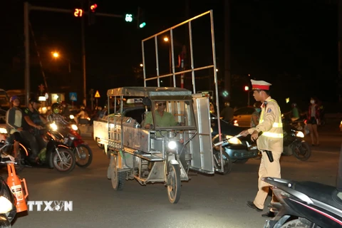 Cảnh sát giao thông Đội 14, Công an thành phố Hà Nội xử lý người điều khiển chở hàng quá khổ tại đường Giải Phóng, Hà Nội. (Ảnh: Doãn Tấn/TTXVN)