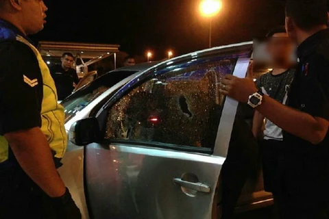 Nạn nhân (che mặt) nói chuyện với cảnh sát bên chiếc xe bị đám 'quái xế​' đập vỡ cửa kính. (Nguồn: nst.com.my)
