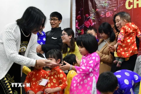 Tổng Lãnh sự Việt Nam tại Fukuoka Nguyễn Phương Hồng phát lì xì mừng tuổi đầu Xuân cho các em nhỏ. (Ảnh: Thành Hữu​/TTXVN​)