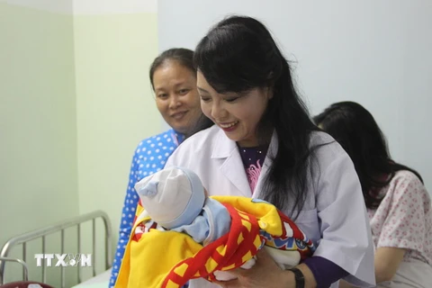 Bộ trưởng Bộ Y tế bế em bé mới chào đời tại Bệnh viện Hùng Vương. (Ảnh: Xuân Dự/TTXVN)