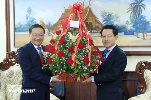 Đại sứ Nguyễn Bá Hùng đang nhờ Bộ trưởng Saleumsay Kommasith chuyển lẵng hoa của Thủ tướng Nguyễn Xuân Phúc tới Thủ tướng Lào Thongloun Sisoulith. (Ảnh: Phạm Kiên/Vietnam+)