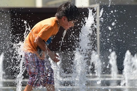 Trẻ em chơi dưới vòi nước để tránh nóng bức tại công viên thành phố Los Angeles, bang California ngày 14/5. (Ảnh: AFP/TTXVN)