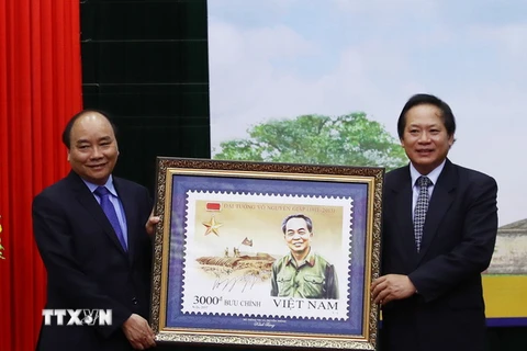 Bộ trưởng Bộ Thông tin và Truyền thông Trương Minh Tuấn thực hiện nghi thức trao tặng bộ tem cho Thủ tướng Nguyễn Xuân Phúc. (Ảnh: Thống Nhất/TTXVN)
