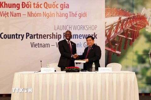 Giám đốc Quốc gia WB tại Việt Nam Ousmane Dione trao sách công bố Khung đối tác Quốc gia cho Bộ trưởng Bộ Kế hoạch và Đầu tư Nguyễn Chí Dũng. (Ảnh: Trần Việt/TTXVN)