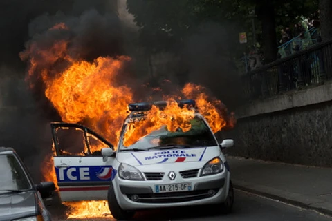 Chiếc xe cảnh sát bốc cháy sau khi bị các đối tượng tấn công. (Nguồn: thelocal.fr)