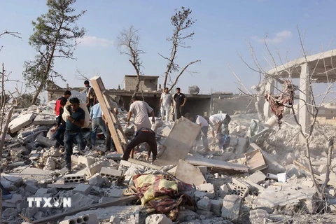 Tìm kiếm các nạn nhân dưói những đống đổ nát sau vụ không kích tại tỉnh Idlib ngày 20/9. (Nguồn: AFP/TTXVN)
