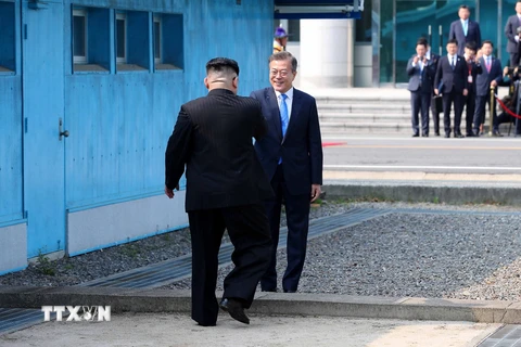 Tổng thống Hàn Quốc Moon Jae-in đón Nhà lãnh đạo Triều Tiên Kim Jong-un (trái) tại đường phân định ranh giới hai miền ở làng đình chiến Panmunjom. (Nguồn: YONHAP/TTXVN)
