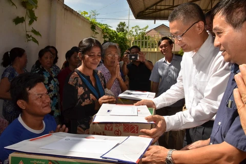 Đại sứ Việt Nam tại Campuchia Vũ Quang Minh (áo trắng) thăm hỏi và tặng quà hỗ trợ cho các bà con. (Ảnh: TTXVN)