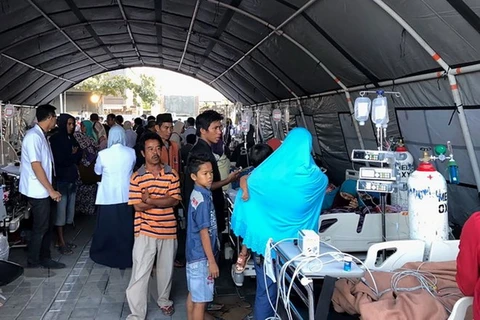 Người dân chờ hỗ trợ y tế tại một bệnh viện tạm sau trận động đất ở Lombok ngày 6/8. (Ảnh: AFP/TTXVN)