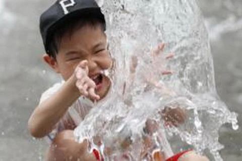 Một bé trai Hàn Quốc nghịch nước để tránh nóng. (Nguồn: BBC)