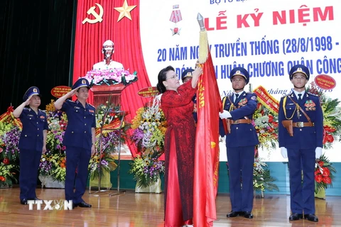 Chủ tịch Quốc hội Nguyễn Thị Kim Ngân gắn Huân chương Quân công hạng Ba lên lá cờ truyền thống của lực lượng Cảnh sát biển Việt Nam. (Ảnh: Trọng Đức/TTXVN)